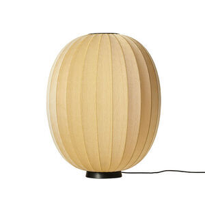 Oval gulvlampe med strikket overflade i lys farve, skaber unikt lysmønster. Elegant og enkel.